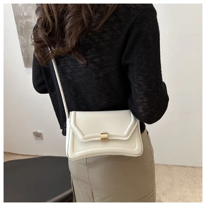 Detail of off-white rectangle saddle bag with gold buckle and textured leather finish