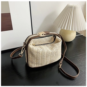 Detail of straw woven crossbody bag with brown leather trim and gold square metal lock