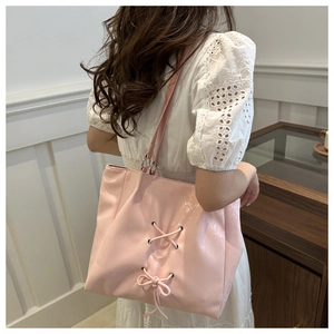 Detailed view of pink ribbon bow accents on high-gloss PU leather tote bag worn by model