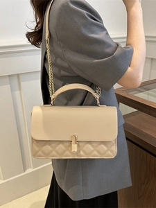 Schicke beige gesteppte Umhängetasche mit Goldbeschlägen an einem eleganten Model
