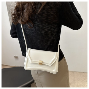 Close-up of minimalist white crossbody saddle bag with gold metal square buckle on model