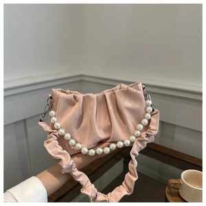 Dettaglio borsa a pieghe rosa chiaro con manico in perle e texture a nuvola