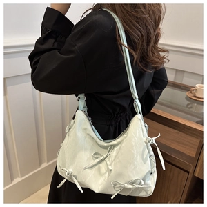 Détail du sac à nœud vert menthe montrant la texture du cuir plissé et le style doux