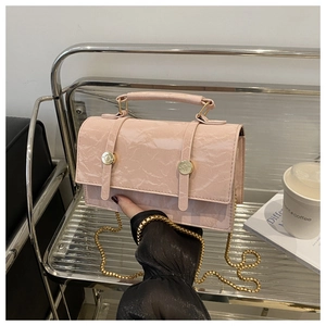 Detail of light pink wrinkled patent leather bag with gold buckle and chain strap
