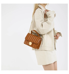 Detail of caramel leather crossbody bag featuring vertical quilting and gold hardware chain