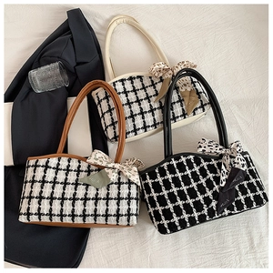 Detailed view of houndstooth tote bags featuring leather handles and decorative silk scarves