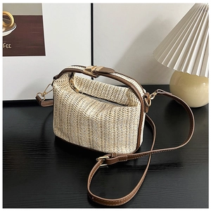 Close-up of woven straw handbag with brown leather trim and golden metal clasp