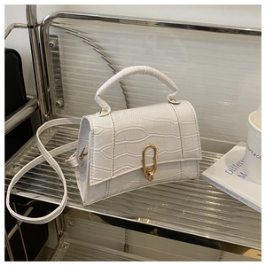 Detailed view of white crocodile pattern handbag with gold lock and top handle
