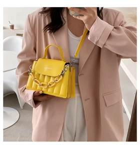 Macro detail of yellow quilted crossbody bag with stylish silver chain and leather strap