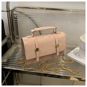 Detail of dusty pink crossbody bag with marble texture, gold chain, and metal buckles