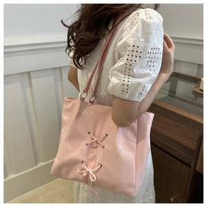 Detailed view of pink leather tote bag featuring stylish lace-up design and metal eyelets