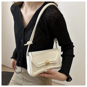 Detail of a creamy white leather saddle bag showing flap closure and gold buckle