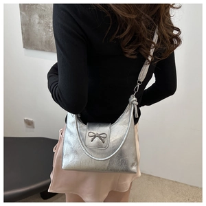 Detail of silver metallic hobo bag featuring a decorative bow and adjustable strap