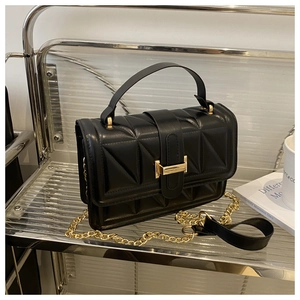 Close-up of black quilted shoulder bag with triangular texture and gold chain strap