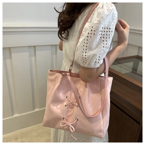 Detail of pink pearlescent tote bag featuring stylish metal eyelets and bow ribbons