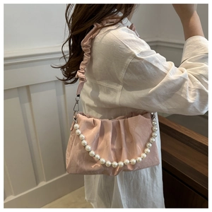 Dettaglio borsa plissettata rosa con catena di perle lucide e trama in raso morbido