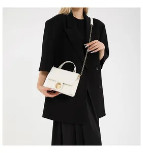 Detailed view of white textured PU leather bag with golden rotary lock and chain strap