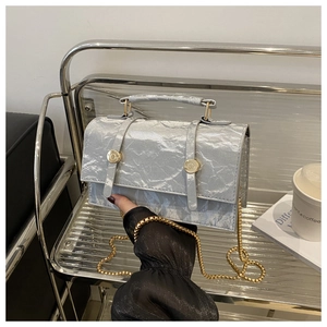 Detail of silver wrinkled texture handbag with gold hardware and chain strap