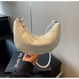 Detail of white leather croissant bag featuring vertical stitching and modern minimalist design