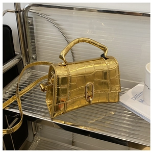 Detailed close-up of metallic gold crocodile embossed handbag with unique curved base