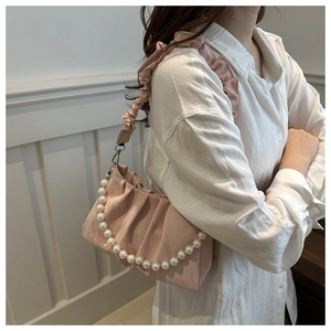 Detail of pink ruched satin bag featuring a pearl handle and ruffled shoulder strap