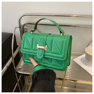 Detail of green quilted crossbody bag showing textured patterns and gold metal hardware