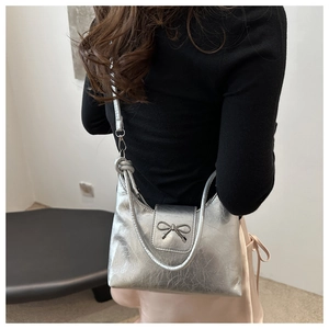 Detail of silver metallic hobo bag with pleated texture and stylish bow buckle