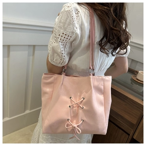 Pink bow tote bag detail featuring lace-up straps and metal eyelets on textured PU leather