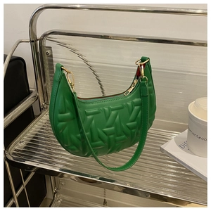Detail view of green crescent bag featuring geometric quilted texture and gold hardware