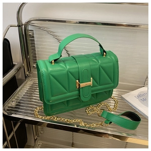 Detail of emerald green quilted crossbody bag with golden metal lock and chain strap