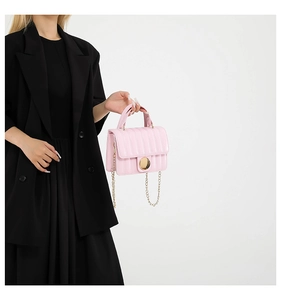 Detailed view of pink quilted handbag with gold chain strap on black blazer