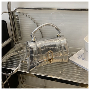 Detailed view of silver crocodile embossed leather texture and curved base on a handbag