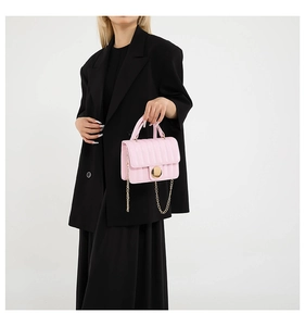 Pink quilted chain crossbody bag shown on a model with a black blazer and gold lock