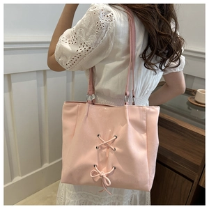 Detail view of the pink tote bag featuring lace-up design and decorative bow on the side