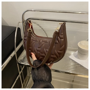 Detail of dark brown quilted crescent bag with embossed texture and red inner lining