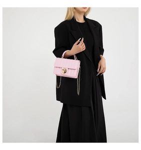 Pink quilted shoulder bag with gold chain strap shown on a model in a black suit