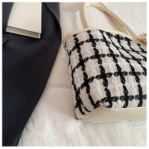 Detail of black and white tweed fabric texture with off-white leather handle on tote bag