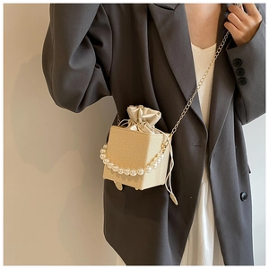 Détail du sac beige texturé avec poignée en perles et bandoulière en chaîne dorée