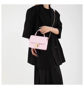 Chic pink quilted crossbody bag with gold chain strap shown on a black suit outfit