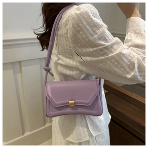 Detail view of a lavender purple saddle bag with golden metal clasp on a lace top