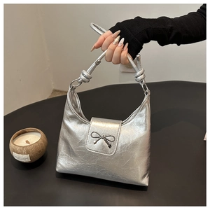 Vue détaillée du sac sous le bras argenté métallisé avec texture et nœud en métal