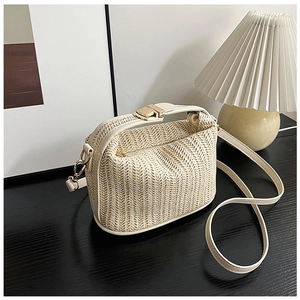 Detail of light beige woven straw shoulder bag with leather handle on wooden table