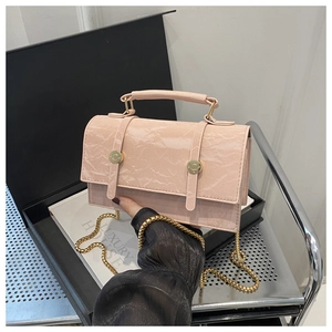 Detail of pink textured leather crossbody bag with gold chain strap and elegant fold finish