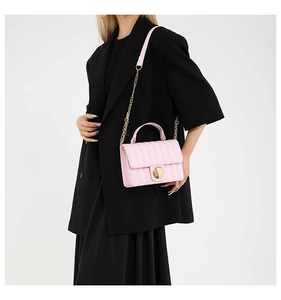 Pink quilted leather bag with round gold buckle and chain strap shown on black suit