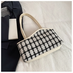 Detail of black and white tweed checkerboard pattern with beige leather shoulder strap