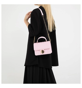 Detail of pink quilted crossbody bag showing vertical stitching and gold turn-lock