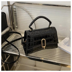 Detail of black faux crocodile skin handbag with glossy finish and gold oval buckle lock