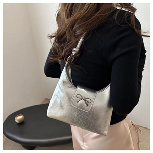 Gros plan du sac hobo argenté avec un nœud métallique décoratif et texture plissée
