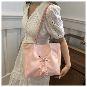 Close-up of pink PU leather tote bag featuring elegant drawstring bow and metal ring detail