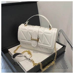 Detail of white quilted crossbody bag with golden metal lock and textured leather finish